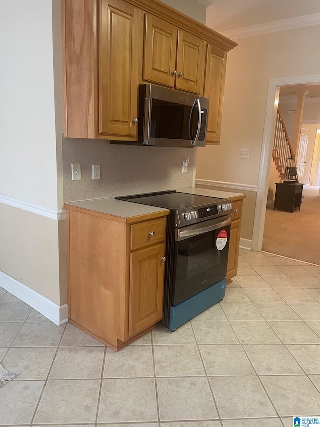 kitchen featuring crown molding, light tile patterned floors, and stainless steel appliances