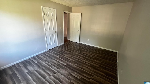 unfurnished room with dark wood-type flooring and a textured ceiling