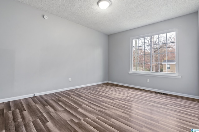 unfurnished room with light wood-style floors, visible vents, a textured ceiling, and baseboards