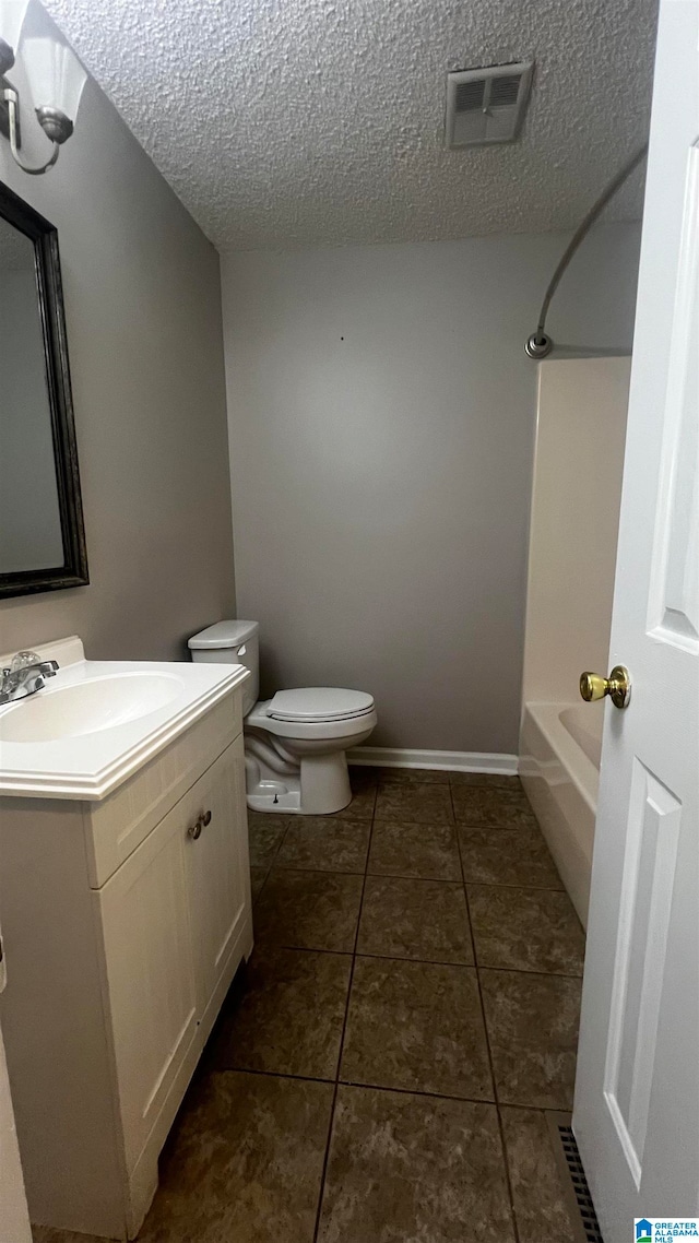 full bathroom with tile patterned flooring, vanity, toilet, and a textured ceiling