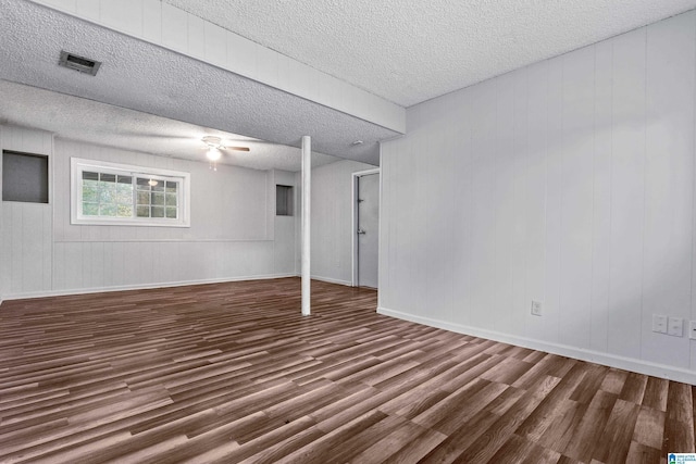 basement with hardwood / wood-style flooring, wood walls, and a textured ceiling