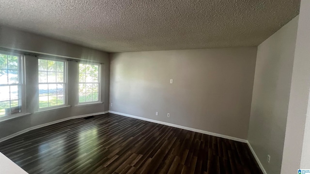 spare room with dark hardwood / wood-style flooring and a textured ceiling