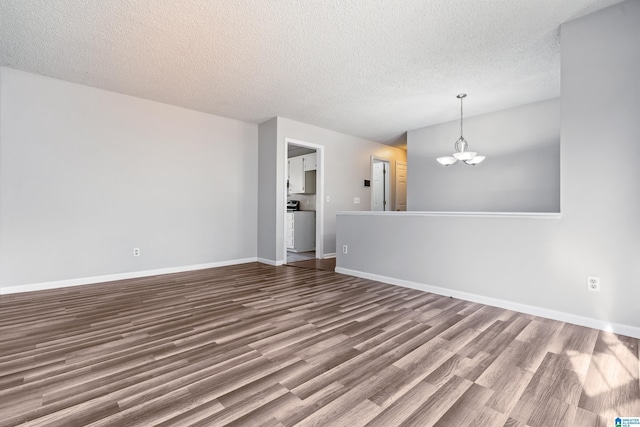 empty room with baseboards, a textured ceiling, wood finished floors, and a notable chandelier