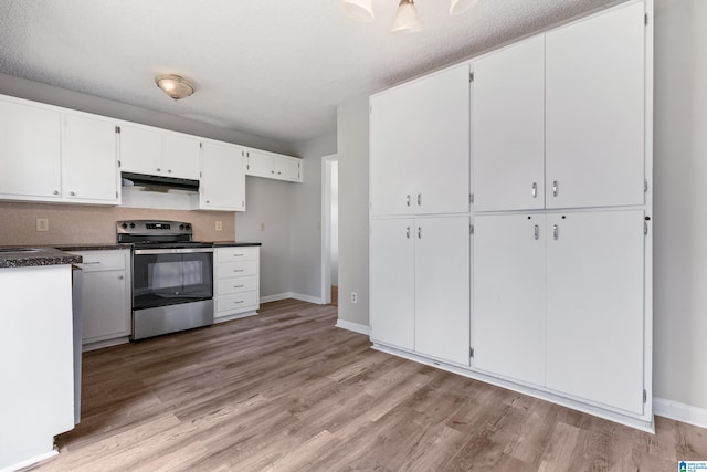 kitchen featuring light wood-style flooring, under cabinet range hood, white cabinetry, stainless steel electric range, and dark countertops