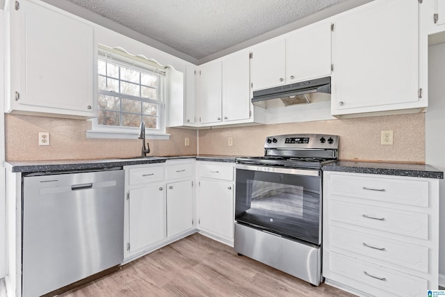 kitchen with appliances with stainless steel finishes, light wood-style flooring, white cabinets, and under cabinet range hood