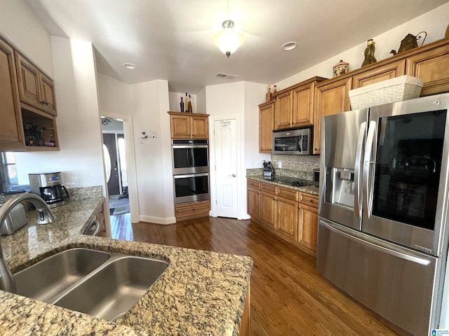 kitchen with sink, dark hardwood / wood-style flooring, stone countertops, and appliances with stainless steel finishes