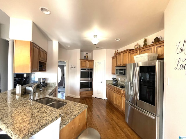 kitchen featuring dark stone counters, appliances with stainless steel finishes, sink, and dark hardwood / wood-style flooring