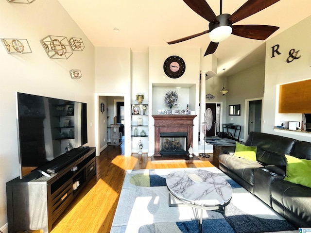 living room featuring ceiling fan, light hardwood / wood-style floors, and a towering ceiling