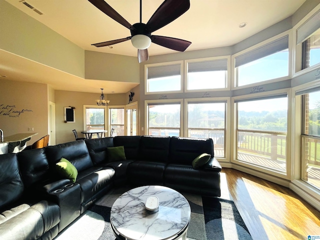 living area featuring plenty of natural light, visible vents, wood finished floors, and ceiling fan with notable chandelier