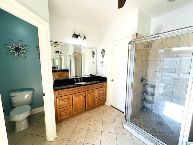 bathroom with toilet, a stall shower, ceiling fan, vanity, and tile patterned flooring