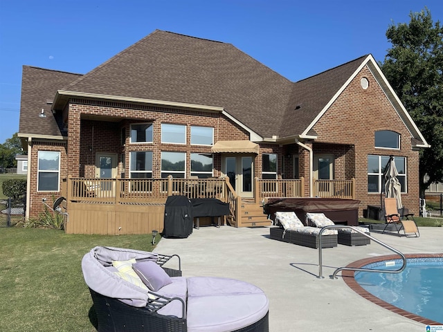 rear view of house with a hot tub, a shingled roof, a wooden deck, a patio area, and brick siding