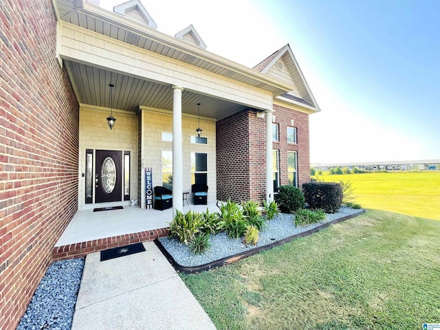 view of exterior entry featuring brick siding and a yard