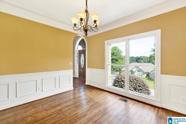 unfurnished room with crown molding, hardwood / wood-style floors, and a chandelier