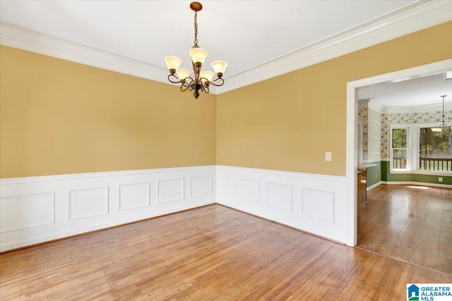 empty room with a chandelier, wood-type flooring, and crown molding