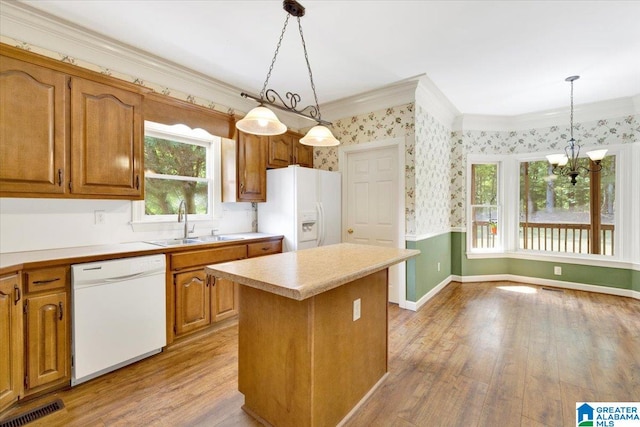 kitchen with white appliances, an inviting chandelier, a wealth of natural light, decorative light fixtures, and a kitchen island