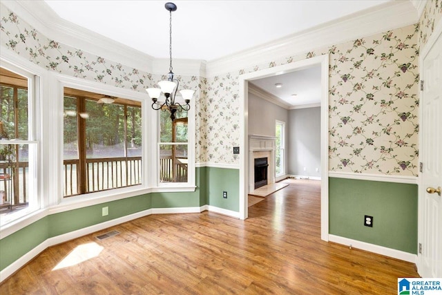 unfurnished dining area featuring hardwood / wood-style floors, a notable chandelier, and ornamental molding