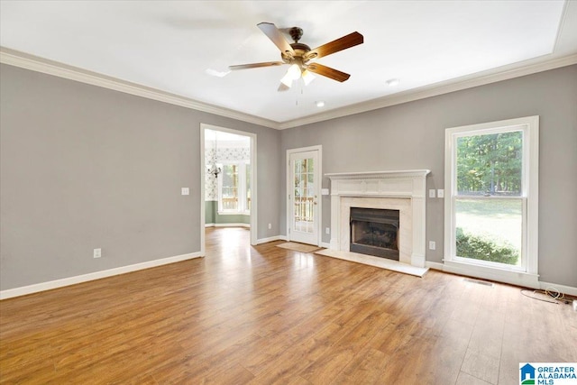 unfurnished living room featuring a premium fireplace, light hardwood / wood-style flooring, a healthy amount of sunlight, and ornamental molding