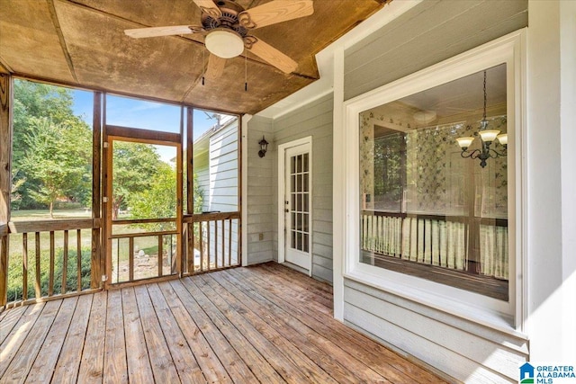 unfurnished sunroom featuring ceiling fan with notable chandelier