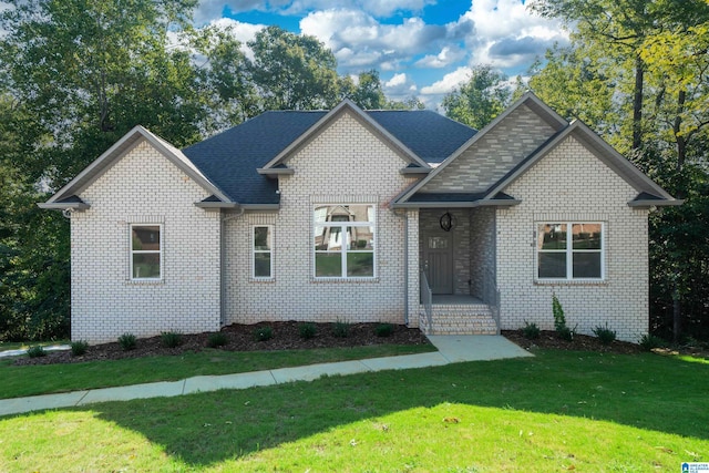 view of front of home with a front yard, brick siding, and roof with shingles