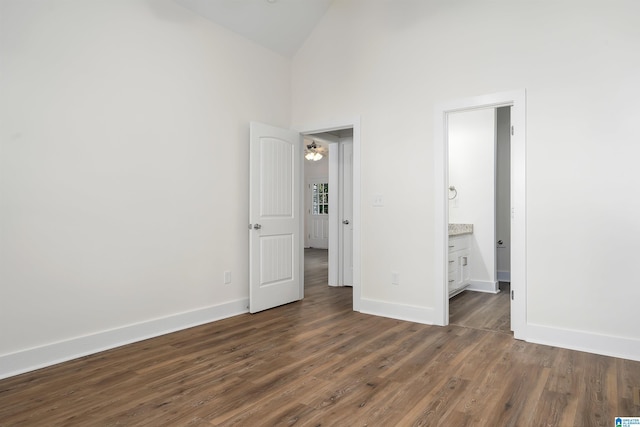 unfurnished bedroom with high vaulted ceiling, dark hardwood / wood-style flooring, and ensuite bath