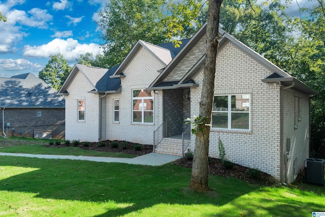 view of front facade featuring central air condition unit, brick siding, and a front yard