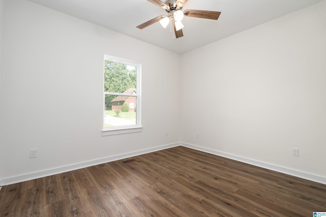 empty room featuring dark wood-style floors, visible vents, a ceiling fan, and baseboards