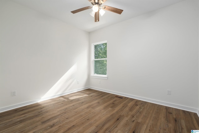 empty room featuring a ceiling fan, dark wood finished floors, visible vents, and baseboards