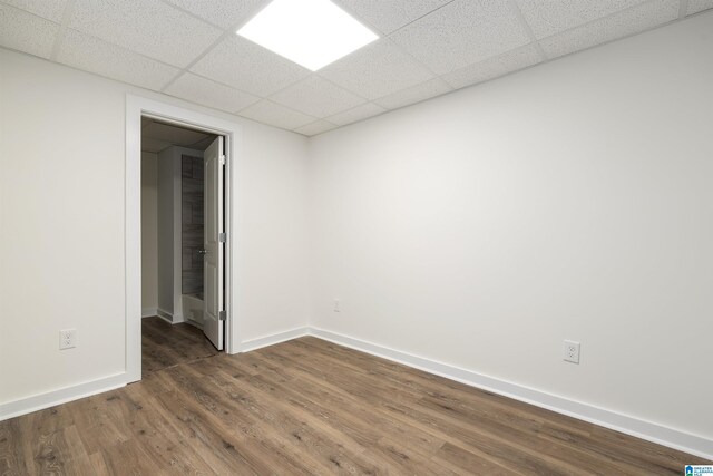 empty room with wood-type flooring and a paneled ceiling