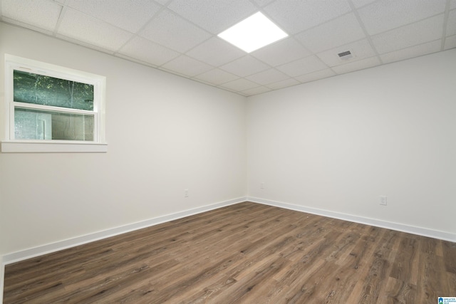 empty room with visible vents, dark wood-style flooring, a paneled ceiling, and baseboards