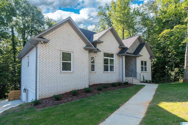 view of front of home featuring an attached garage, brick siding, and a front yard