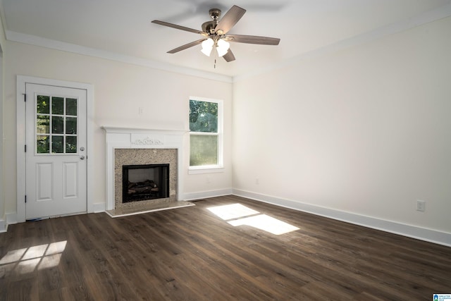 unfurnished living room with dark wood-style flooring, a fireplace, ornamental molding, a ceiling fan, and baseboards