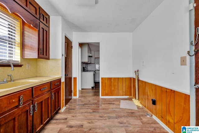 kitchen with sink, a textured ceiling, and light hardwood / wood-style flooring