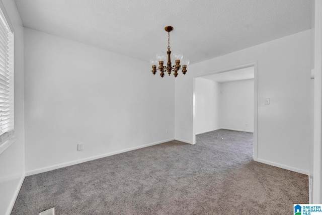 carpeted spare room featuring a textured ceiling and a notable chandelier