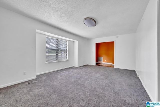 unfurnished room with a textured ceiling and carpet flooring