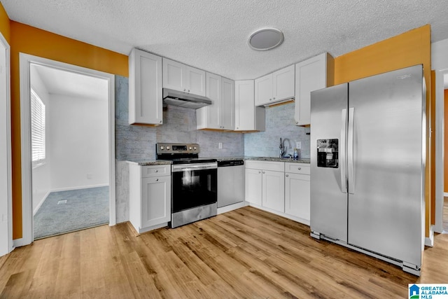 kitchen featuring light carpet, tasteful backsplash, white cabinetry, appliances with stainless steel finishes, and light stone counters