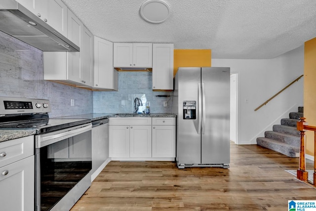 kitchen with light hardwood / wood-style floors, ventilation hood, stainless steel appliances, and white cabinetry