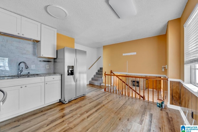 kitchen with plenty of natural light, light hardwood / wood-style floors, light stone counters, and stainless steel refrigerator with ice dispenser