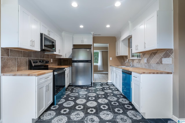 kitchen with wooden counters, backsplash, dark tile patterned flooring, stainless steel appliances, and white cabinets