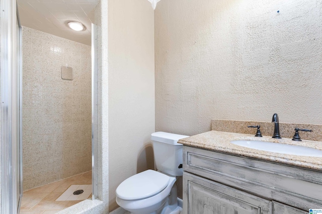 bathroom featuring toilet, a tile shower, and vanity