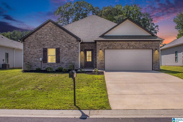 view of front of house with a garage, a lawn, and cooling unit