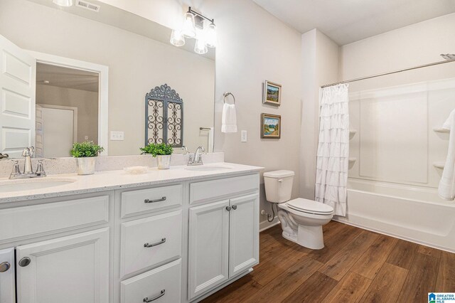 bathroom with double vanity, wood finished floors, a sink, and toilet