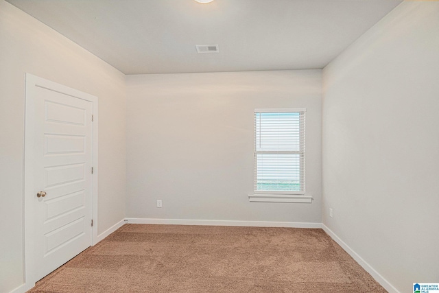 spare room with baseboards, visible vents, and light colored carpet