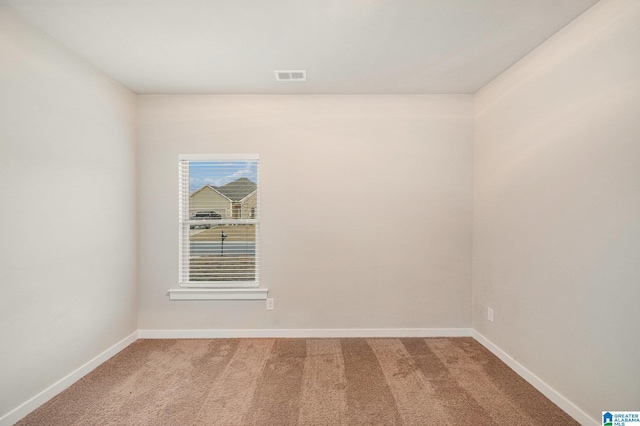 spare room with visible vents, light carpet, and baseboards