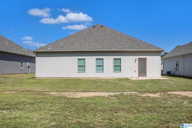 rear view of house with central AC, a yard, roof with shingles, and a patio area