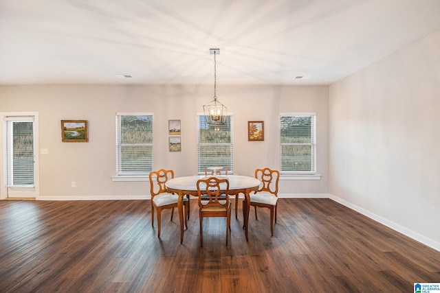 dining room featuring a chandelier, dark wood finished floors, and baseboards