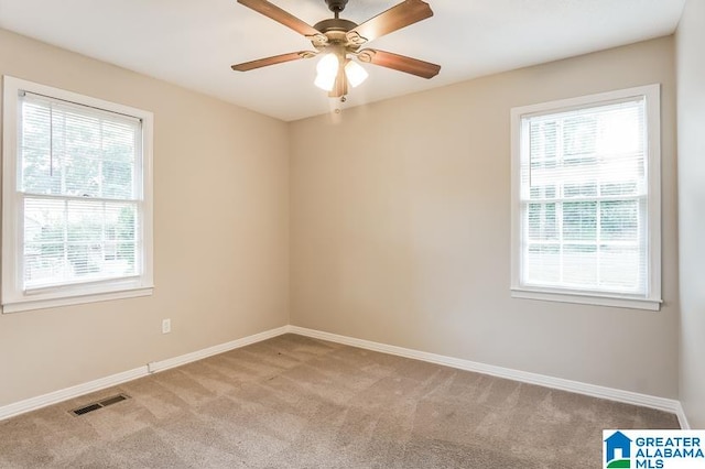 spare room featuring ceiling fan, a healthy amount of sunlight, and light colored carpet