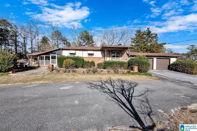 view of front facade featuring driveway, an attached garage, and a sunroom