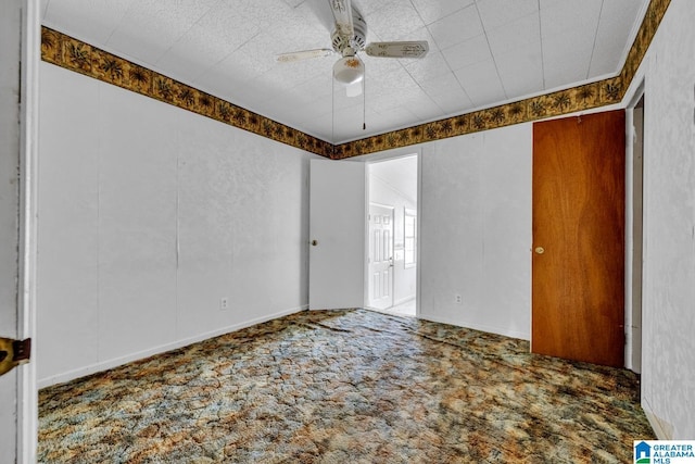 unfurnished room with ceiling fan and carpet