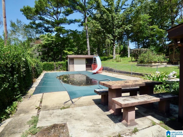 view of pool featuring a shed, a patio, a jacuzzi, and a water slide