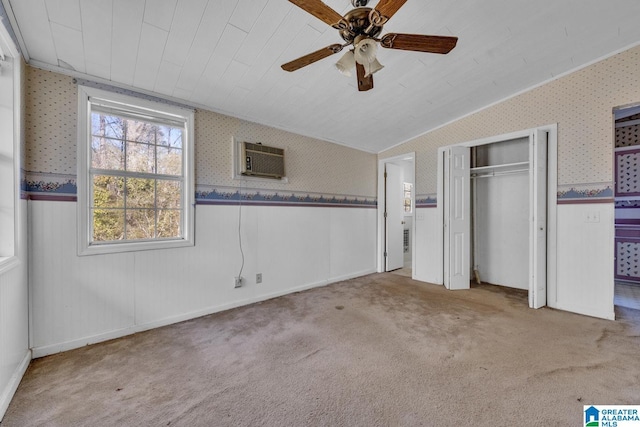 unfurnished bedroom with ceiling fan, a wall mounted AC, and light carpet